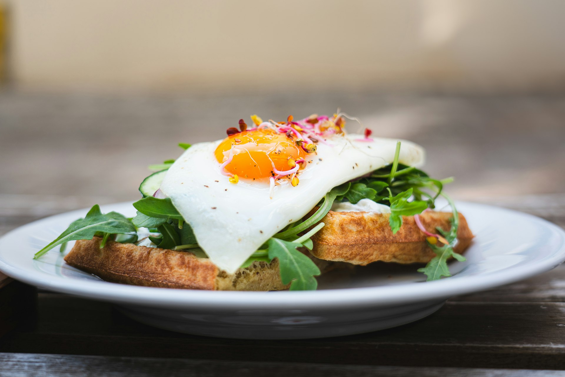 A white plate topped with an egg and greens